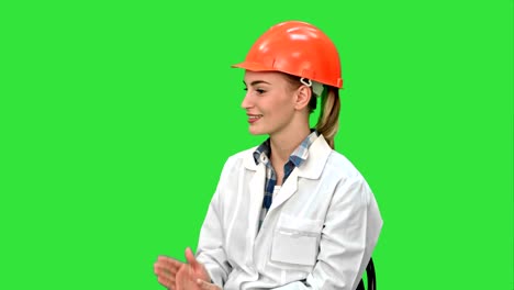 Female-engineer-in-safety-helmet-sitting-and-talking-on-a-Green-Screen,-Chroma-Key