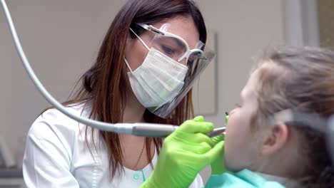 Dentista-limpia-los-dientes-de-la-muchacha-con-pasta-dental-profesional.-Chica-con-dientes-blancos-en-la-oficina-del-dentista.-Rodada-en-4k