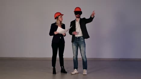 Two-construction-engineers-in-helmets-with-VR-goggles-managing-building-project-in-3d