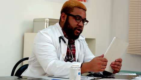 African-american-male-doctor-explaining-xray-results-to-patient-via-video-call-on-tablet