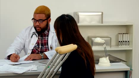 African-american-doctor-giving-medical-paper-to-a-young-woman-on-crutches