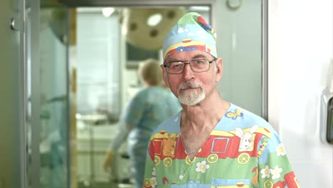 Smiling-senior-doctor-looking-at-the-camera-in-hospital-surgery-examination-room