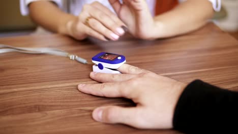 Pulse-oximeter,-placed-on-an-unrecognizable-man's-finger-is-examining-his-heart-rate-and-pulse-during-medical-check-up.-Shot-in-4k