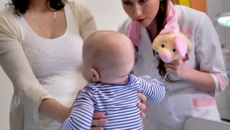 A-doctor-distracts-a-toddler-with-a-plushy-pig.