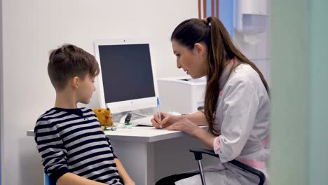 Friendly-doctor-writes-prescription-for-young-boy.