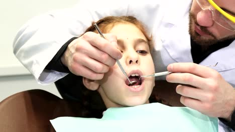 A-serious-doctor-carefully-examines-the-upper-teeth-of-the-young-patient