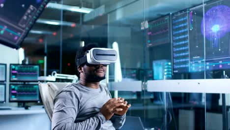 Im-Labor-Wissenschaftler-interagiert-tragen-Virtual-Reality-Kopfhörer-in-einem-Sessel-sitzend-mit-Monitore-mit-Gehirn-Aktivität-Informationen.-Moderne-Brain-Studie-/-neurologische-Forschungszentrum.