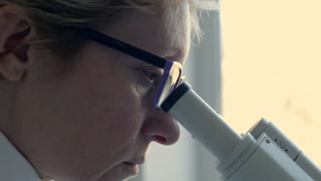 Female-scientist-looking-through-microscope