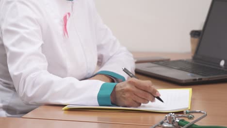 Cropped-shot-of-a-female-doctor-writing-notes-using-her-laptop-at-work
