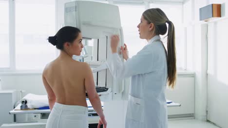 In-the-Hospital,-Mammography-Technologist-/-Doctor-adjusts-Mammogram-Machine-for-a-Female-Patient.-Friendly-Doctor-Explains-Importance-of-Breast-Cancer-Prevention-Screening.-Modern-Technologically-Advanced-Clinic-with-Professional-Doctors.