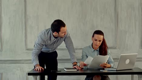 two-colleagues-discuss-around-laptop-computer