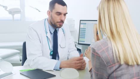 Plastic-/-Cosmetic-Surgeon-Shows-Female-Patient-Breast-Implant-Samples-for-Her-Future-Surgery.-Professional-and-Famous-Surgeon-Working-in-Respectable-Clinic.