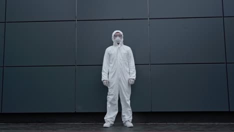 asian-scientist-in-protective-suit-standing-near-building