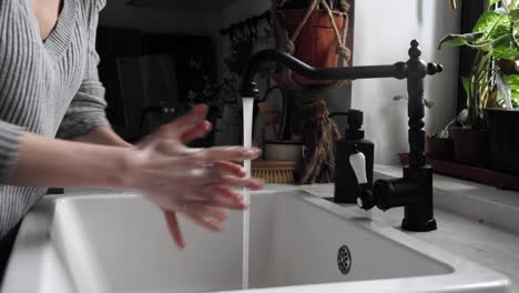 Woman-washing-hands-in-kitchen-at-home,-video