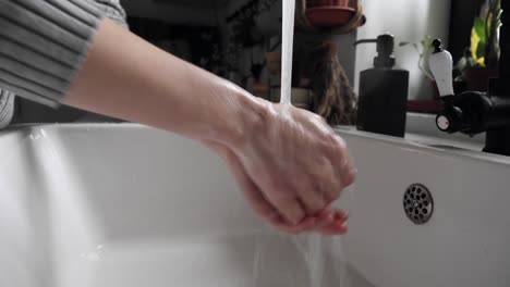 Woman-washing-hands-in-kitchen-at-home,-video