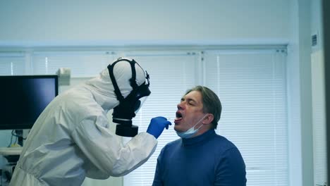 Paramédico-en-traje-de-salpicaduras-está-tomando-la-saliva-del-paciente-para-una-prueba.-Detección-de-pacientes-covid-19,-síntomas-del-coronavirus.