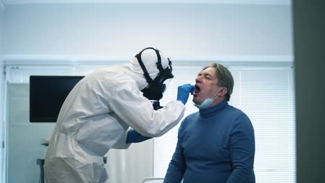 Un-trabajador-de-la-clínica-toma-el-frotis-del-hombre-para-la-prueba-del-coronavirus-durante-la-pandemia-del-coronavirus.-Coronavirus,-covid-19-Paciente-infectado-durante-la-prueba-en-el-hospital.