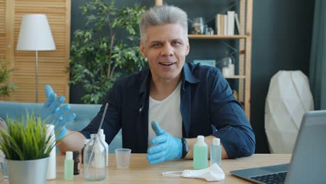 Portrait-of-adult-man-making-hand-sanitizer-at-home-holding-bottles-looking-at-camera-talking