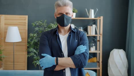 Portrait-of-guy-standing-at-home-wearing-reusable-cotton-face-mask-during-epidemic