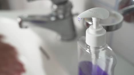 Young-Man-Using-Soap-Dispenser,-then-Washing-Hands-on-background