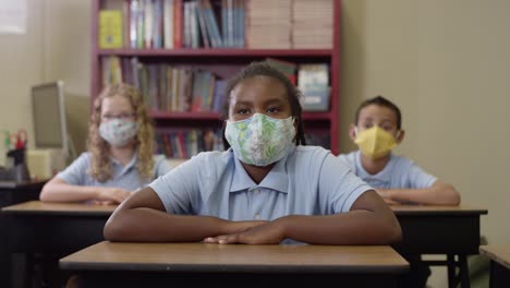 Los-estudiantes-jóvenes-usan-máscaras-y-escuchan-en-clase-y-luego-la-chica-negra-levanta-la-mano