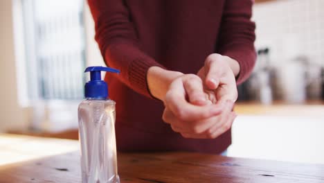 Mid-section-of-woman-sanitizing-her-hands-at-home