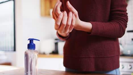 Mid-section-of-woman-sanitizing-her-hands-at-home