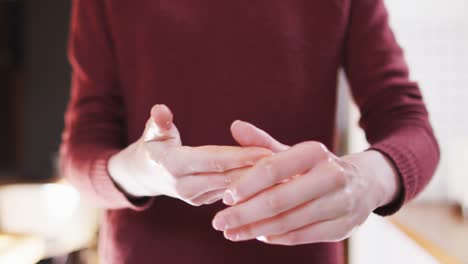 Mid-section-of-woman-sanitizing-her-hands-at-home