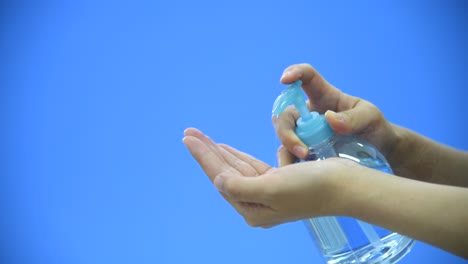 Woman-clean-hands-with-hand-sanitizer-on-blue-background