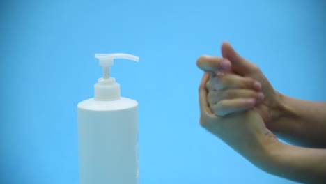 Frau-saubere-Hände-mit-Handdesinfektionsmittel-auf-blauem-Hintergrund