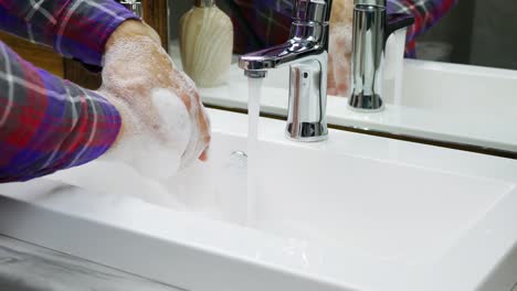 Wash-hands-under-a-tap-with-water,a-person-very-carefully-protects-himself-from-the-COVID-19-virus,wash-his-hands-in-foam,wash-off-dirt-from-his-hands,close-up