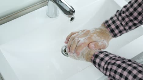 Young-man,a-man-washing-his-hands-under-a-tap-with-water,to-prevent-infection-with-coronavirus,close-up.To-wash-off-the-dirt-from-his-hands