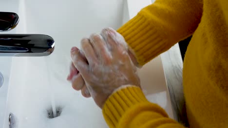 Washing-hands-under-a-tap-with-soap-and-water,close-up,a-young-man-washes-away-dirt-from-his-hands.