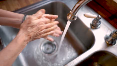 Mujer-lavándose-las-manos-en-un-fregadero-de-acero-inoxidable-a-cámara-lenta