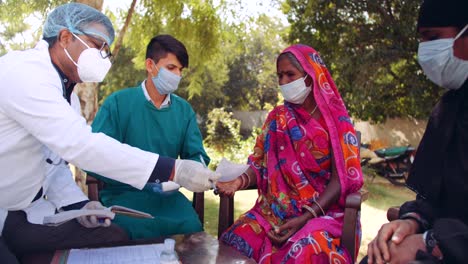 Médicos-médicos-al-aire-libre-con-una-mujer-de-la-tercera-edad-en-las-zonas-rurales-de-la-India