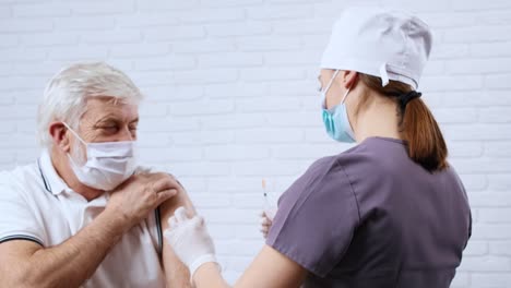 Krankenschwester-in-Uniform-geben-Impfstoff-für-Patienten-in-Schutzmaske.