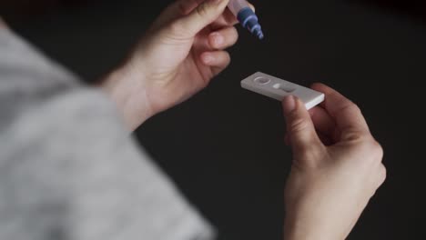 Mujer-haciendo-prueba-auto-casera-coronavirus-kit-de-hisopo-nasal-para-posible-infección-covid-19-en-casa-durante-el-aislamiento-de-bloqueo---Enfoque-en-la-mano-izquierda