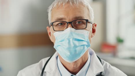 Close-Up-Portrait-eines-älteren-kaukasischen-männlichen-Arztes-oder-Chirurgen,-der-eine-schützende-Gesichtsmaske-und-eine-Brille-trägt.-Middle-Aged-Scientist-Calmly-Looking-at-Camera.-Medizinische-Versorgung-Spezialist-in-Covid-19-Realität.