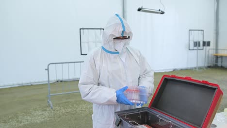 Man-in-protective-suit-with-mask-holding-sample-of-swab-after-a-drive-through-test-for-covid-19.-Infection-prevention-and-control-of-epidemic.