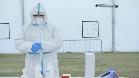 Hombre-en-traje-protector-con-máscara-que-sostiene-la-muestra-de-hisopo-después-de-una-prueba-de-conducción-para-covid-19.-Prevención-y-control-de-infecciones-epidémicas.