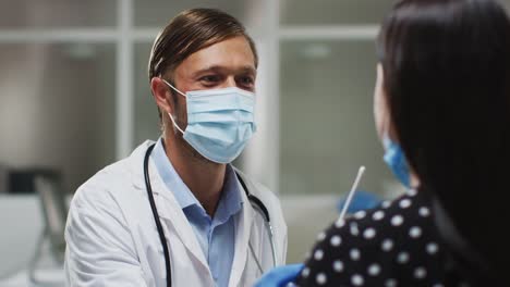 Médico-caucásico-hombre-usando-máscara-facial-y-guantes-tomando-prueba-de-hisopo-del-paciente