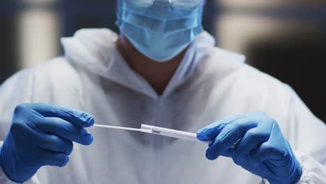 Medical-worker-in-protective-clothing-and-face-mask-examining-patient-swab-test