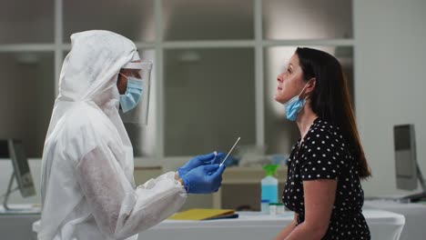 Medical-worker-in-protective-clothing-taking-swab-test-from-female-patient