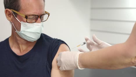 a-male-patient-watches-as-he-is-vaccinated-in-the-arm