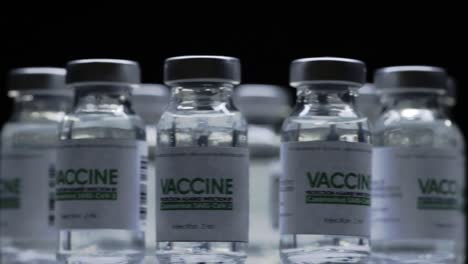 Bottles-of-vaccine-for-COVID-19-coronavirus-cure-are-quickly-rotated-in-research-lab.-Vaccination,-injection,-clinical-trial-during-pandemic.-Vials,-flasks-are-spinning-clockwise.-Wide-macro-in-dark