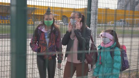 A-Mother-and-two-daughters-in-a-protective-anti-virus-mask-walk-along-the-street-in-an-isolated-area.