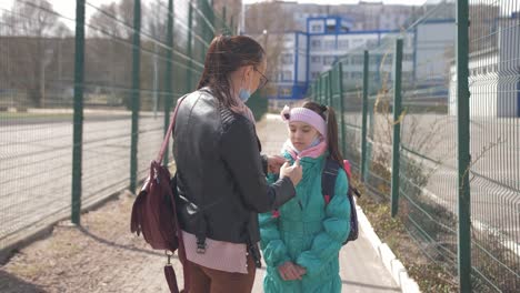 Mutter-und-Tochter-in-Schutzmasken-gehen-zur-Schule.