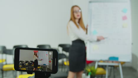 Female-English-teacher-in-glasses-having-online-class-on-smartphone.-Woman-assigning-homework-for-students.-Education-concept.-Quarantine-concept.-Study-by-internet.