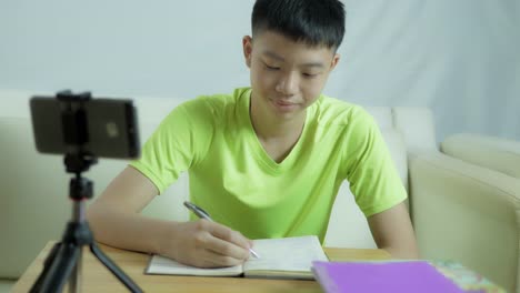 Un-adolescente-asiático-de-pelo-negro-está-estudiando-en-línea-en-casa-con-Smart-Phone