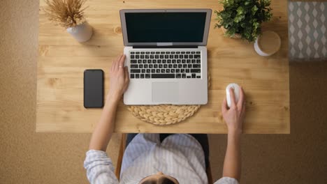 Das-Mädchen-arbeitet-aus-der-Ferne-über-das-Internet.-Sitzen-an-seinem-Laptop.-Ansicht-von-oben.-Holztisch.-Beige-Farben.-Das-Konzept-des-E-Learning-von-zu-Hause-aus.-Selektiver-Fokus.